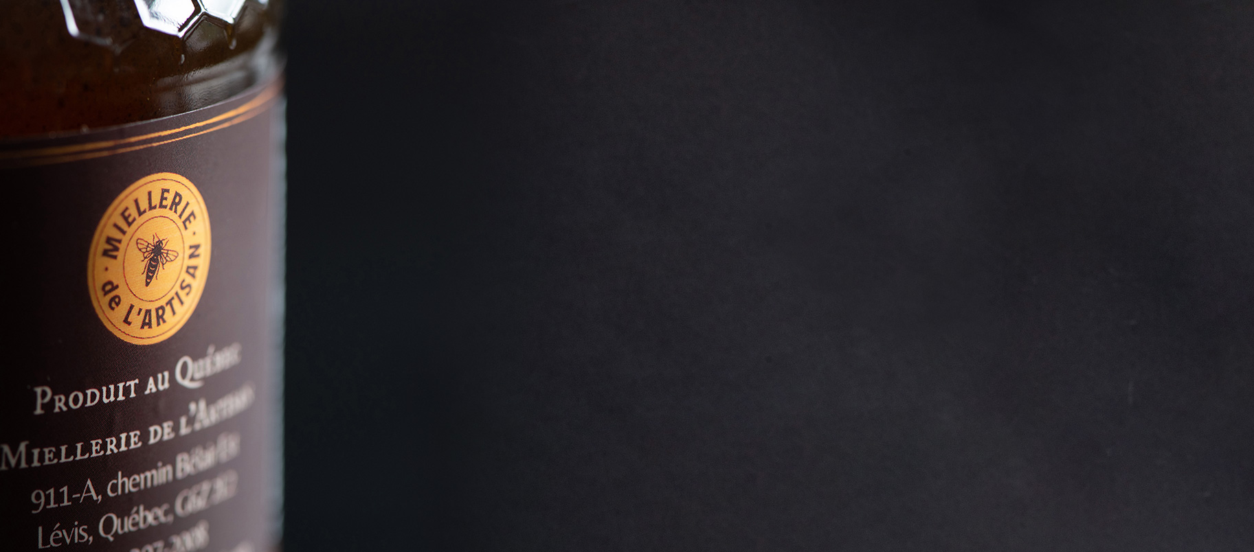 Pot de miel de l'Artisan du Québec avec étiquette et logo d'abeille.