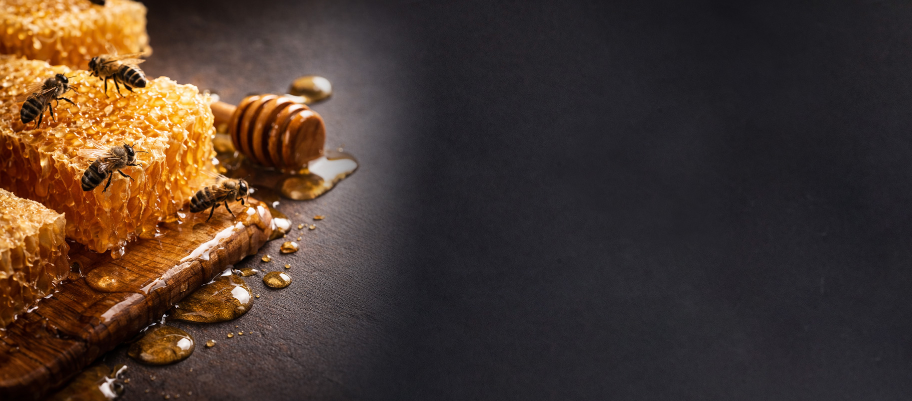 Rayons de miel avec abeilles, miel dégoulinant et cuillère à miel en bois sur une planche à découper.