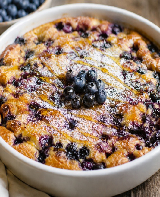 Clafoutis aux bleuets sauvages, garni de bleuets frais et de sucre glace.